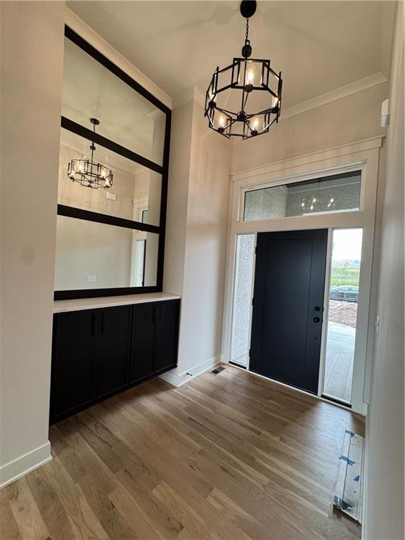 9019 Freedom Cir, Lenexa, KS 66227 - entrance foyer with a chandelier, baseboards, wood finished floors, and crown molding