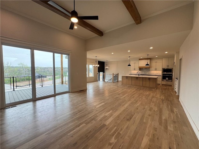 9019 Freedom Cir, Lenexa, KS 66227 - unfurnished living room with beamed ceiling, wood finished floors, a chandelier, a ceiling fan, and baseboards