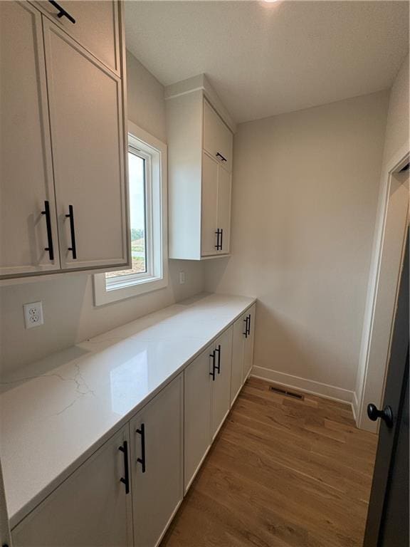 9019 Freedom Cir, Lenexa, KS 66227 - kitchen with light wood-type flooring, white cabinets, and baseboards