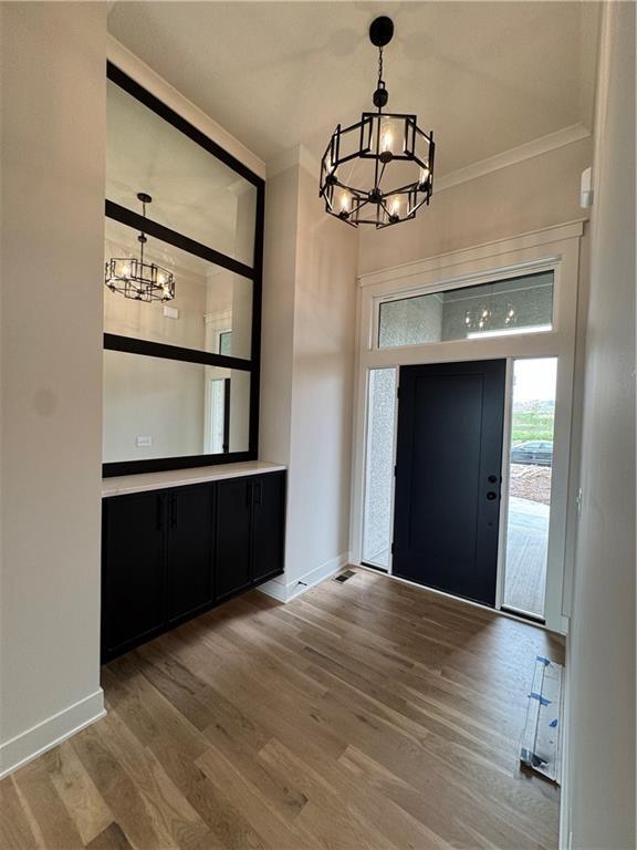 9019 Freedom Cir, Lenexa, KS 66227 - entryway featuring a chandelier, wood finished floors, and ornamental molding