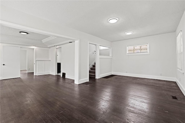 3218 Benton Blvd, Kansas City, MO 64128 - unfurnished living room with stairway, a textured ceiling, dark wood-type flooring, and baseboards