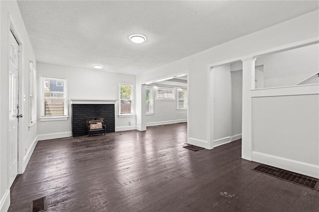 3218 Benton Blvd, Kansas City, MO 64128 - unfurnished living room featuring baseboards, a textured ceiling, and dark wood-style flooring