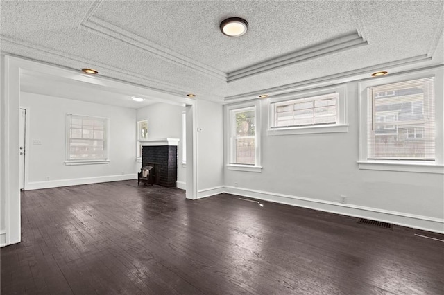 3218 Benton Blvd, Kansas City, MO 64128 - unfurnished living room featuring a textured ceiling, healthy amount of natural light, dark wood-style floors, a fireplace, and baseboards