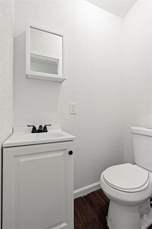 3218 Benton Blvd, Kansas City, MO 64128 - bathroom featuring wood finished floors, vanity, toilet, baseboards, and a textured wall