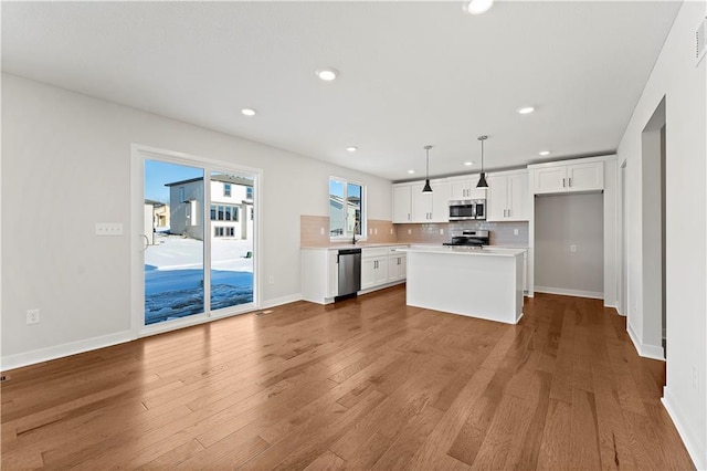 338 Meadowlark Dr, Raymore, MO 64083 - kitchen featuring stainless steel appliances, white cabinets, light countertops, recessed lighting, and decorative backsplash
