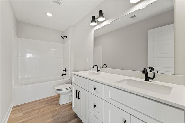 338 Meadowlark Dr, Raymore, MO 64083 - bathroom featuring toilet, wood finished floors, double vanity, bathtub / shower combination, and recessed lighting