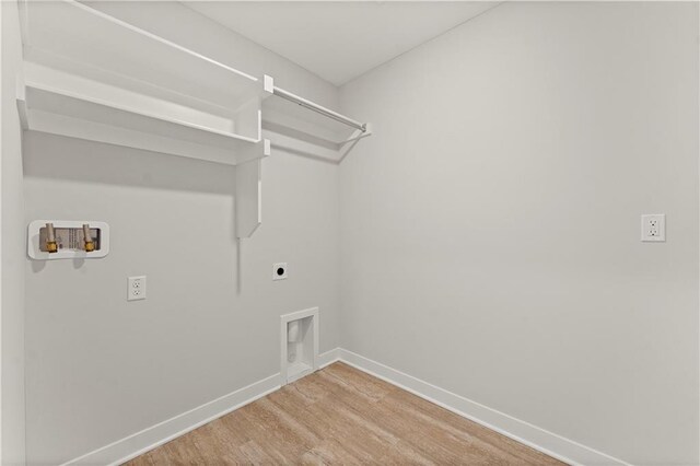 338 Meadowlark Dr, Raymore, MO 64083 - laundry area with electric dryer hookup, washer hookup, baseboards, and wood finished floors