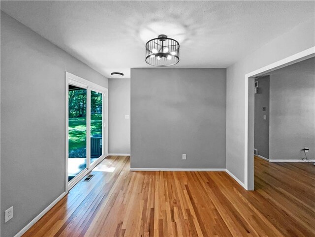 11709 Fremont Ave, Kansas City, MO 64134 - empty room featuring wood finished floors, a chandelier, baseboards, and a textured ceiling