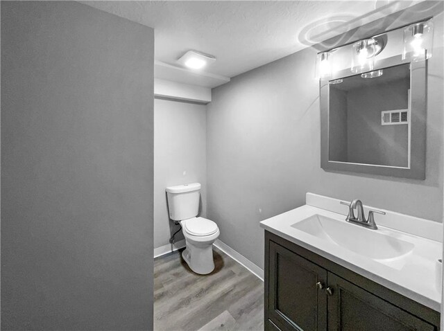 11709 Fremont Ave, Kansas City, MO 64134 - half bath with wood finished floors, toilet, vanity, baseboards, and a textured ceiling