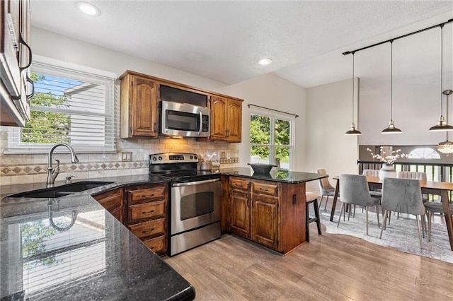 21607 W 51st St, Shawnee, KS 66226 - kitchen with appliances with stainless steel finishes, a peninsula, light wood finished floors, dark stone countertops, and recessed lighting