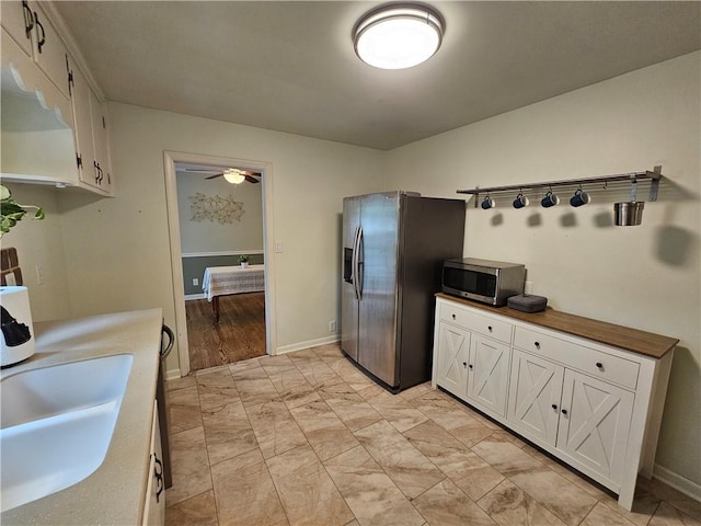 11306 E 45th St, Kansas City, MO 64133 - kitchen with stainless steel appliances, ceiling fan, white cabinets, light marble finish floors, and a sink
