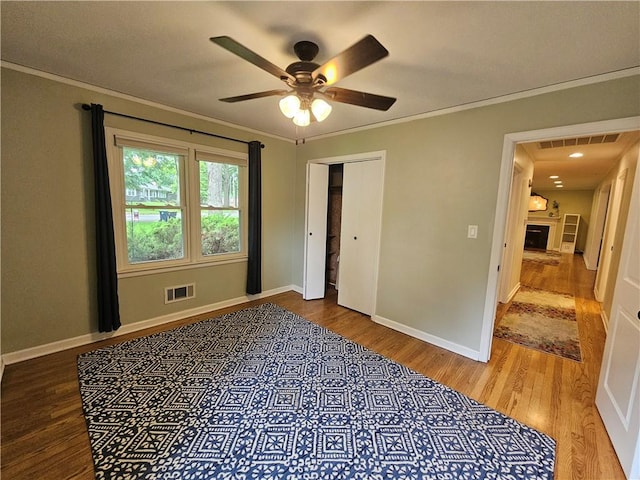 11306 E 45th St, Kansas City, MO 64133 - unfurnished bedroom with wood finished floors, crown molding, baseboards, a ceiling fan, and a closet