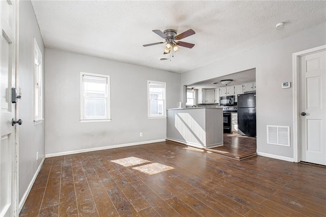 212 S Delaware St, Tonganoxie, KS 66086 - unfurnished living room featuring a ceiling fan, baseboards, a textured ceiling, and dark wood finished floors