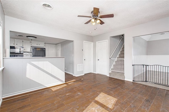 212 S Delaware St, Tonganoxie, KS 66086 - unfurnished living room featuring a ceiling fan, a textured ceiling, wood finished floors, stairs, and baseboards