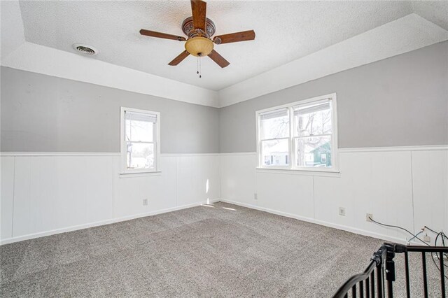 212 S Delaware St, Tonganoxie, KS 66086 - carpeted spare room featuring a textured ceiling, wainscoting, and ceiling fan