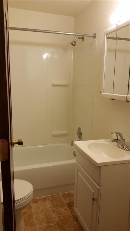 1903-05 High Grove Rd, Grandview, MO 64030 - full bath featuring shower / washtub combination, toilet, vanity, and stone finish flooring