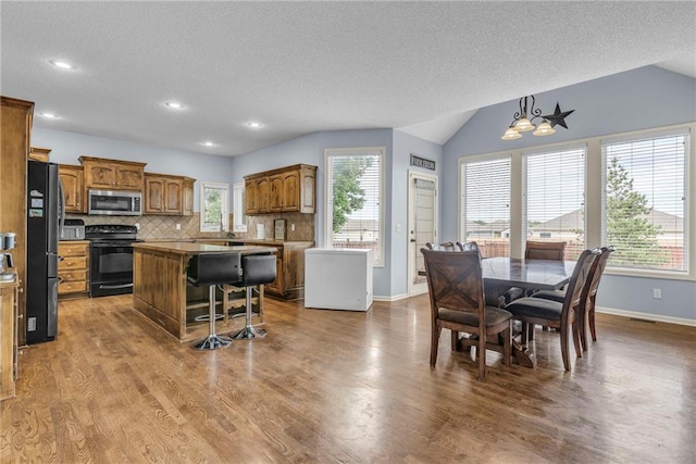 635 N Laurel St, Gardner, KS 66030 - kitchen featuring black appliances, brown cabinets, a kitchen island, a textured ceiling, and baseboards