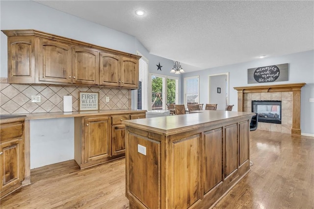 635 N Laurel St, Gardner, KS 66030 - kitchen featuring light wood-style floors, a textured ceiling, a center island, tasteful backsplash, and a chandelier