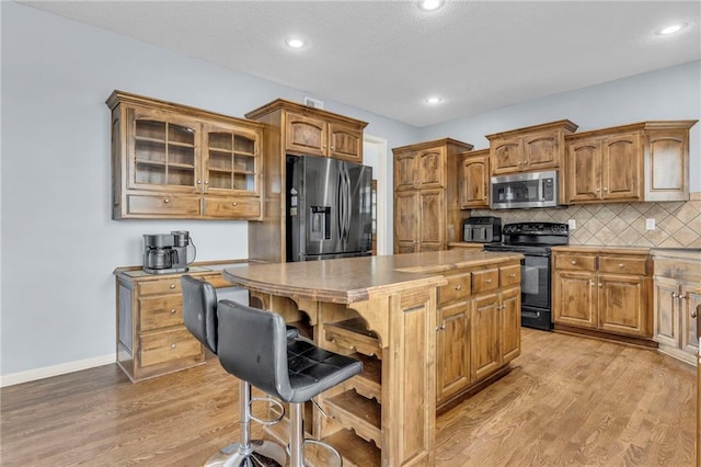 635 N Laurel St, Gardner, KS 66030 - kitchen featuring stainless steel appliances, a center island, light wood-style flooring, a kitchen bar, and brown cabinets