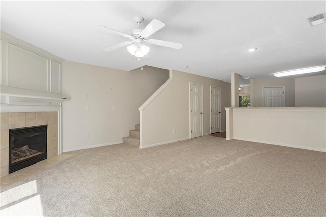 5412 Fairmount Ave, Kansas City, MO 64118 - unfurnished living room featuring ceiling fan, light colored carpet, a tiled fireplace, stairway, and baseboards