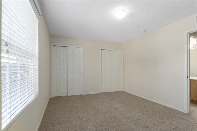 5412 Fairmount Ave, Kansas City, MO 64118 - unfurnished bedroom with multiple closets, carpet flooring, baseboards, and a textured ceiling