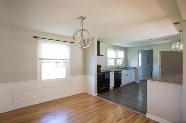 7048 Horton St, Overland Park, KS 66204 - kitchen featuring black appliances, wall chimney range hood, a chandelier, wainscoting, and wood finished floors