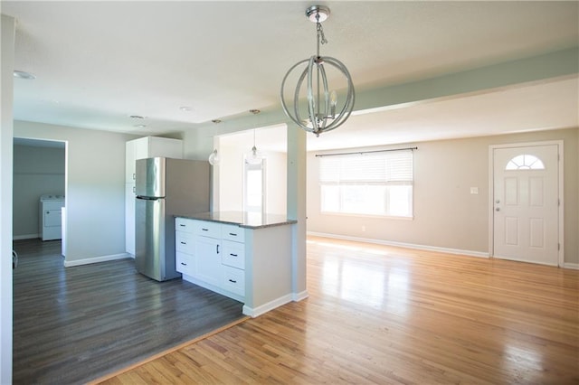 7048 Horton St, Overland Park, KS 66204 - kitchen with freestanding refrigerator, washer / clothes dryer, white cabinets, a chandelier, and light wood-style flooring