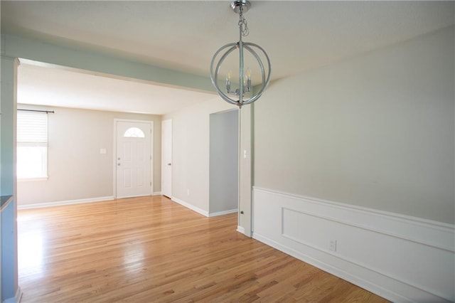 7048 Horton St, Overland Park, KS 66204 - unfurnished dining area featuring a chandelier, light wood-style floors, and wainscoting