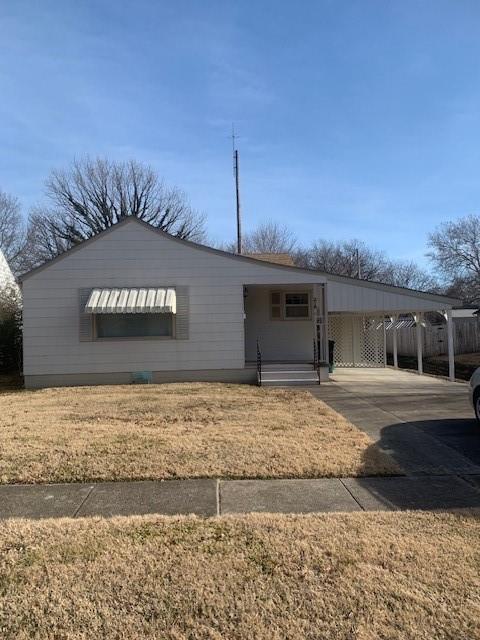 218 29th St, Parsons, KS 67357 - view of front of home featuring an attached carport, a front lawn, and concrete driveway