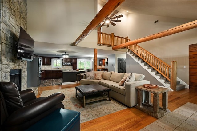 611 N Winnebago Dr, Lake Winnebago, MO 64034 - living room with ceiling fan, stairs, a fireplace, high vaulted ceiling, and light wood-type flooring