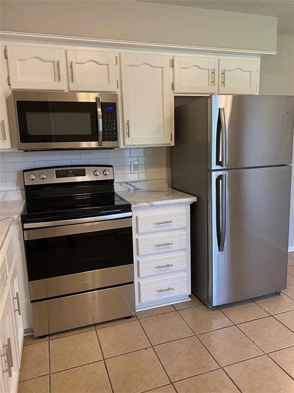 11307 W 60th St, Shawnee, KS 66203 - kitchen featuring stainless steel appliances, white cabinets, light tile patterned floors, backsplash, and a textured ceiling