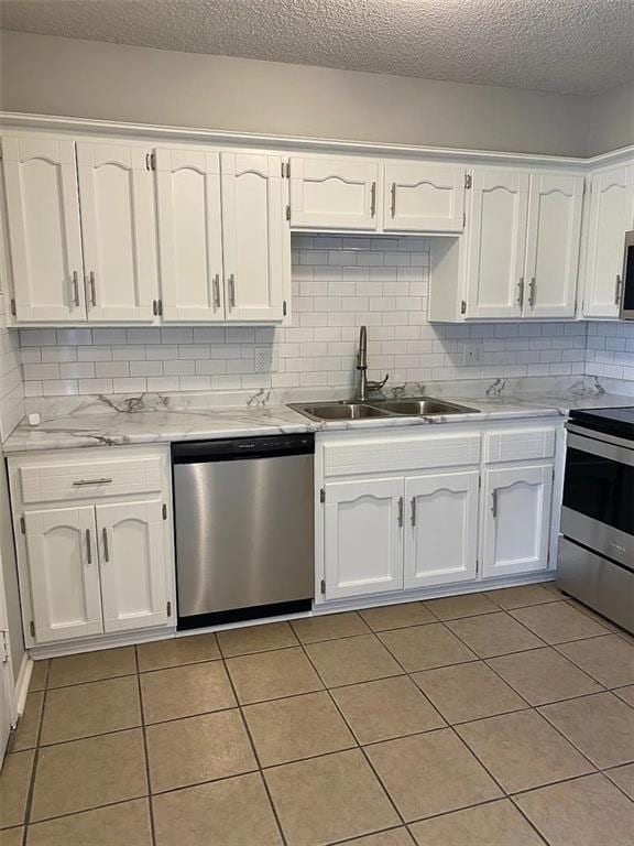 11307 W 60th St, Shawnee, KS 66203 - kitchen featuring appliances with stainless steel finishes, a sink, white cabinetry, light tile patterned floors, and a textured ceiling