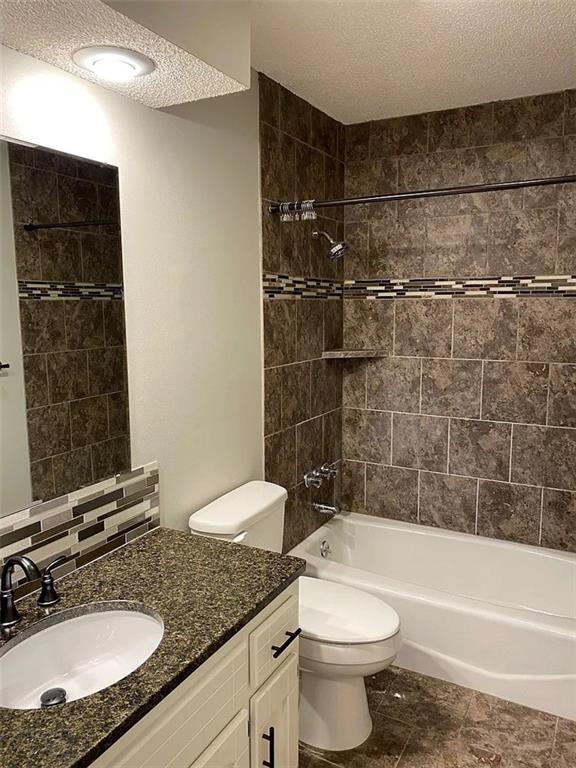 11307 W 60th St, Shawnee, KS 66203 - bathroom with a textured ceiling, toilet, washtub / shower combination, vanity, and tile patterned flooring