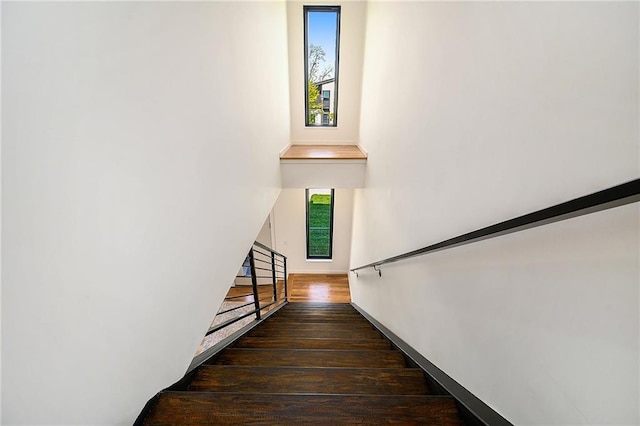 stairway with wood finished floors, healthy amount of natural light, and baseboards