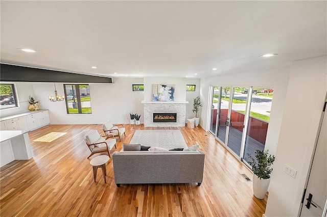 living area featuring a glass covered fireplace, recessed lighting, and light wood finished floors