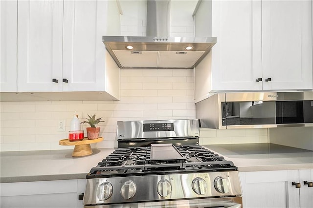 kitchen with wall chimney range hood, stainless steel range with gas cooktop, white cabinets, light countertops, and backsplash