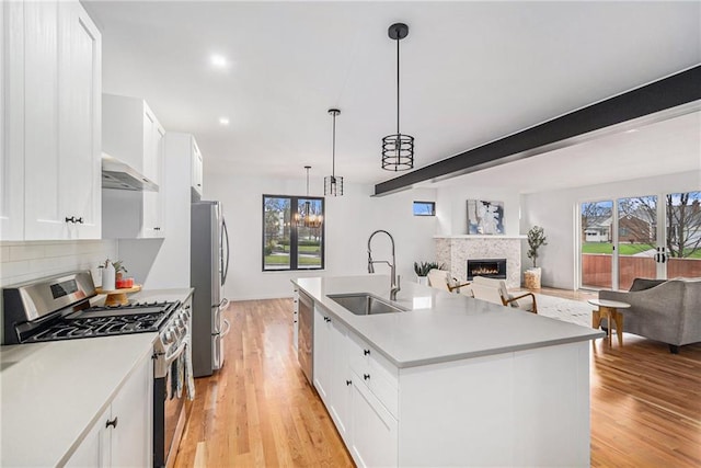 2605 W Paseo Blvd, Kansas City, MO 64108 - kitchen featuring stainless steel appliances, open floor plan, a sink, a lit fireplace, and decorative backsplash