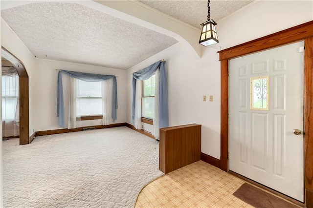 3121 Saint Joseph Ave, Saint Joseph, MO 64505 - entrance foyer with arched walkways, a textured ceiling, baseboards, and light carpet