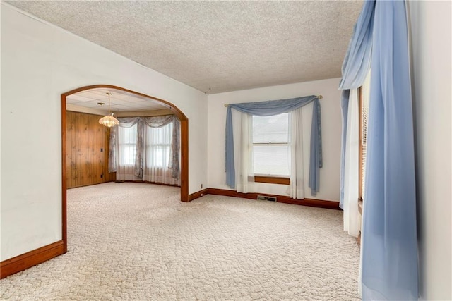 3121 Saint Joseph Ave, Saint Joseph, MO 64505 - empty room featuring arched walkways, carpet, baseboards, a textured ceiling, and a chandelier
