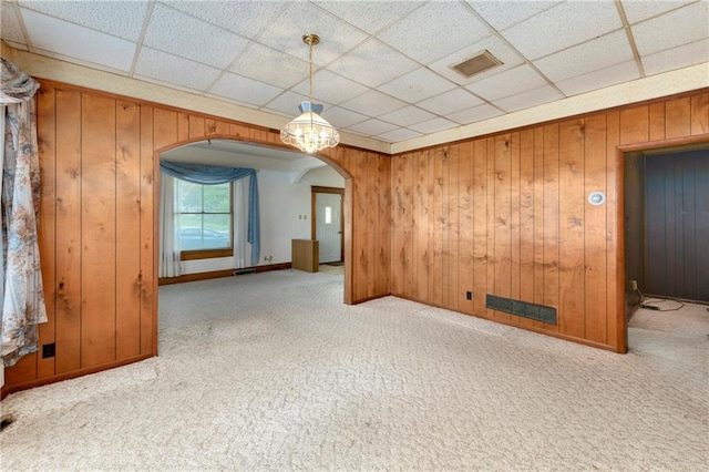 3121 Saint Joseph Ave, Saint Joseph, MO 64505 - carpeted empty room with arched walkways, wooden walls, a drop ceiling, and baseboards