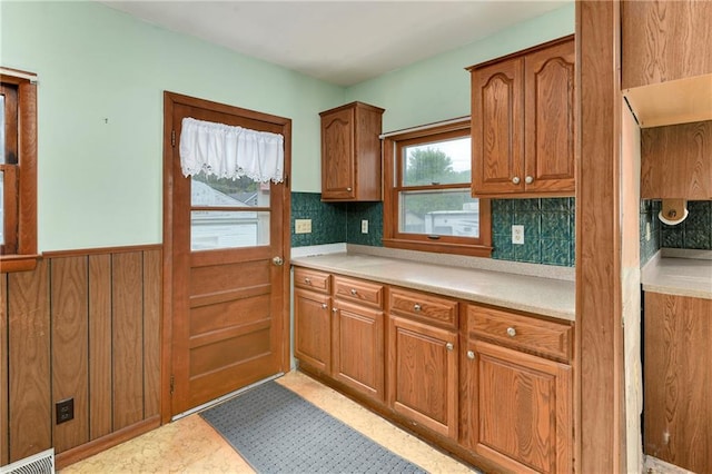 3121 Saint Joseph Ave, Saint Joseph, MO 64505 - kitchen featuring brown cabinets, light countertops, a wainscoted wall, and tasteful backsplash