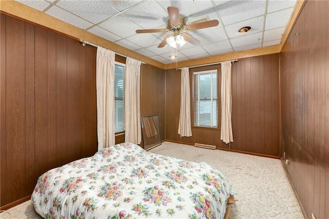 3121 Saint Joseph Ave, Saint Joseph, MO 64505 - carpeted bedroom with multiple windows, wood walls, a drop ceiling, and ceiling fan