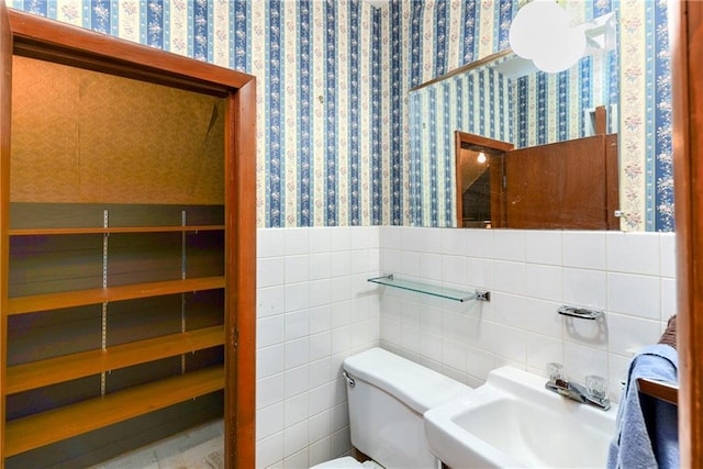 3121 Saint Joseph Ave, Saint Joseph, MO 64505 - half bath featuring a sink, wallpapered walls, toilet, a wainscoted wall, and tile walls