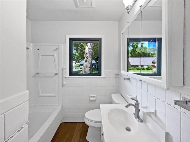 7139 Hardy St, Overland Park, KS 66204 - full bath featuring a sink, toilet, tile walls, wood finished floors, and tub / shower combination