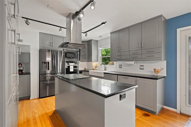 9520 Lamar Ave, Overland Park, KS 66207 - kitchen featuring appliances with stainless steel finishes, island exhaust hood, gray cabinetry, dark countertops, and light wood-style flooring