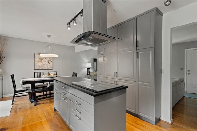 9520 Lamar Ave, Overland Park, KS 66207 - kitchen with island range hood, gray cabinets, dark countertops, light wood-style flooring, and track lighting