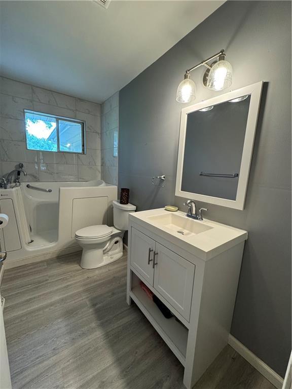 6705 E 140th Pl, Grandview, MO 64030 - full bathroom featuring wood finished floors, a bath, toilet, and vanity