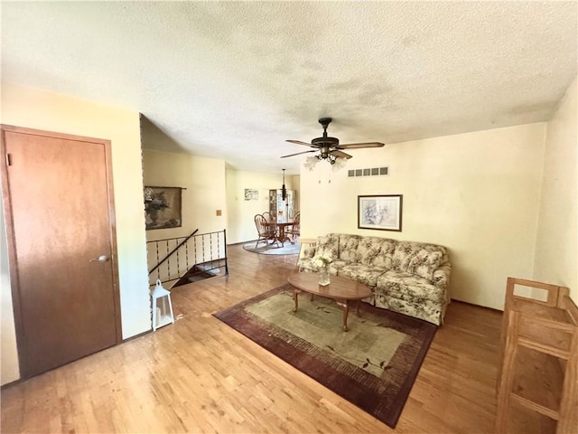 6705 E 140th Pl, Grandview, MO 64030 - living area with wood finished floors, a ceiling fan, and a textured ceiling
