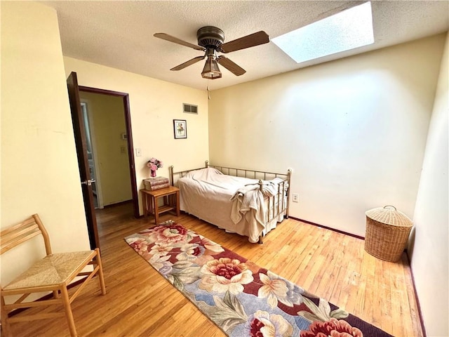 6705 E 140th Pl, Grandview, MO 64030 - bedroom with a skylight, wood finished floors, a ceiling fan, and a textured ceiling