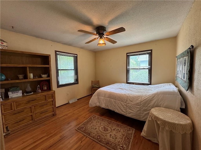 6705 E 140th Pl, Grandview, MO 64030 - bedroom featuring multiple windows, wood finished floors, a textured ceiling, and ceiling fan